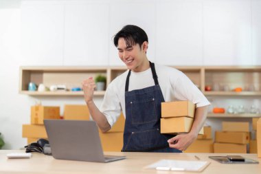 Genç bir girişimci, e-ticaret işini yönetirken sevinç ifadesi sergiliyor..