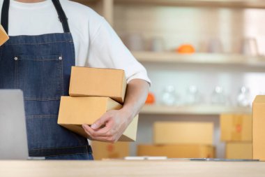 Bir çalışan, modern bir çalışma alanında çeşitli kutuları dengeler ve onları etkin bir e-ticaret operasyonunda nakliyeye hazırlar..