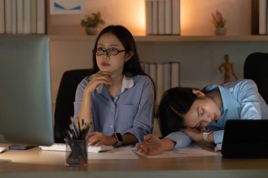 Meslektaşlar görevlerine odaklanırken, biri dinlenirken, diğeri verileri analiz ediyor, takım çalışmasını ve adanmışlığı vurguluyor.