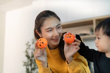 Neşeli bir anne ve oğlu Cadılar Bayramı temalı dekorasyonlarla oynuyorlar, yaratıcılık ve aile bağlarını gösteriyorlar..