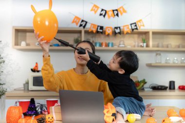 Bir anne ve oğlu cadılar bayramı balonları ile neşeli bir anı paylaşıyor, evdeki şenlik ruhunu canlandırıyor..