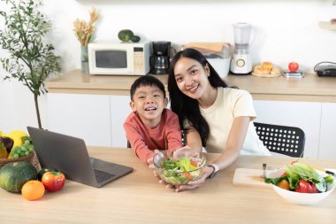 Bir ebeveyn ve çocuk bir kase salatayla birlikte gülümsüyor, sağlıklı beslenmenin ve aile etkileşiminin önemini gösteriyor..