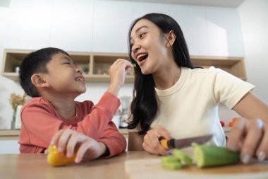 Sebzeleri birlikte hazırlayan bir anne ve oğlu arasındaki hoş bir etkileşim sağlıklı yemek pişirmeyi ön plana çıkarıyor..