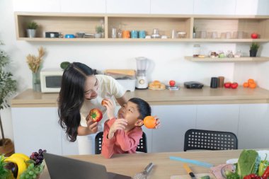 Bir anne ve oğlu taze meyveleri birlikte seçmekten, sağlıklı beslenme alışkanlıklarını geliştirmekten ve canlı bir mutfak ortamında aile etkileşiminden hoşlanırlar..