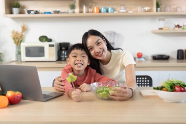 Bir ebeveyn ve çocuk salata hazırlarken mutfaktaki sağlıklı beslenme ve aile bağlarını vurguladı..