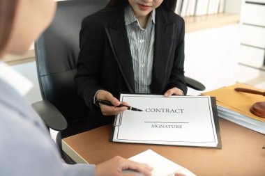 Profesyonel bir kadın, yasal anlaşmaların iş dünyasındaki önemini vurgulayan bir sözleşmeyi müşteriyle tartışıyor..