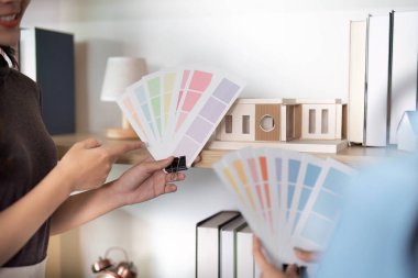 İç tasarımcılar renk örneklerini ve mimari modelleri değerlendirir, işbirliği ve tasarım yeniliklerini vurgularlar.