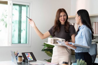 İki kadın mimar, ortak bir ortamda bir yapı modeli ve renk örnekleri sergileyerek yaratıcı bir tartışmaya giriştiler..