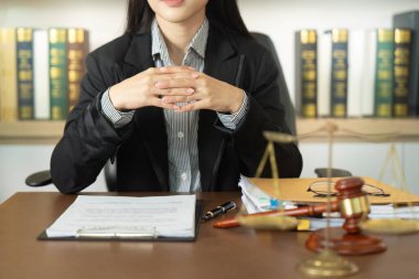 Odaklanmış bir iş kadını masasında oturuyor, bir müşteriyle hukuki konuları tartışmaya hazır, profesyonelliğini gösteriyor..