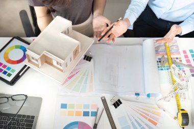 Renk örnekleri ve bir modelle bir proje planlayan tasarımcılar, ortak bir çalışma alanında fikir ve stratejileri tartışıyor.