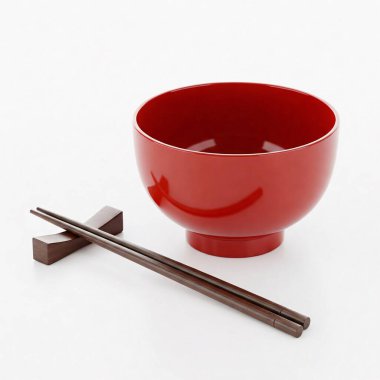 Bir çift çubuk ve yemek çubuğuyla kırmızı kase..