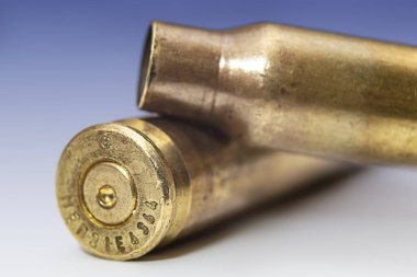 two machine gun cartridge cases on color gradient background close up