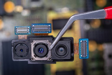 Akıllı telefonun cımbızla çekilmiş üçlü kamerasına yakın çekim