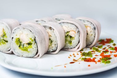 Canlı bir tabak taze suşi, sulu deniz ürünleri ve sağlıklı ürünlerden yapılmış kabarık beyaz pirinç yatağının üzerinde..