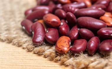 Ahşap yüzeydeki jüt kumaşın üstünde kırmızı fasulye.