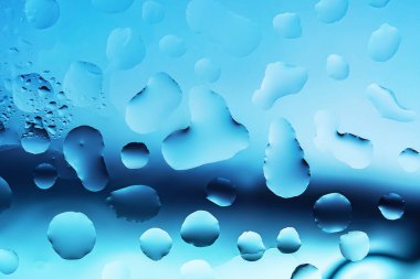 Camdan bir yüzeye su damlıyor. Yaklaş.