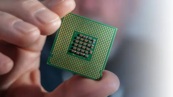 The man is holding a CPU chip in LGA package close up