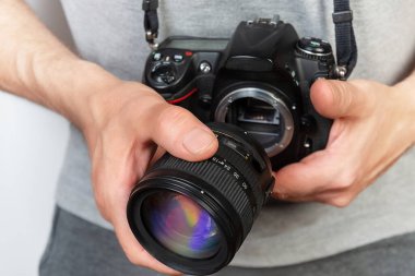 Dijital tek lensli refleks (DSLR) kamera tutan ve kamera lensini takan bir fotoğrafçının yakın çekimi