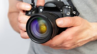 Dijital bir kamera tutarken kamera lensini ayarlayan bir kişinin yakın çekimi.
