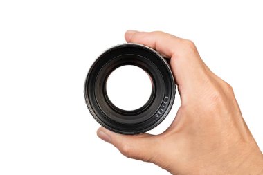 Bir el beyaz arka planda kamera lensini tutuyor..