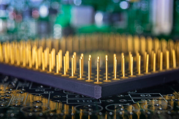 Detailed close-up image of a computer microprocessor with golden pins on a green circuit board, depicting technology and electronics.