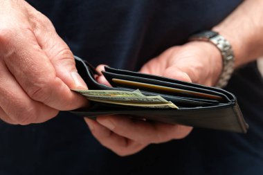 Bir kişinin cüzdan açması, nakit ve kredi kartlarını göstermesi, kişisel finans ve harcamaları sembolize etmesi,.