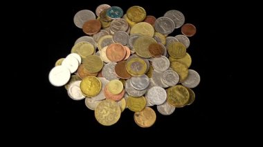 Kadının elleri siyah bir arkaplanın önünde duran bir yığın madeni parayı tırmıklıyor..