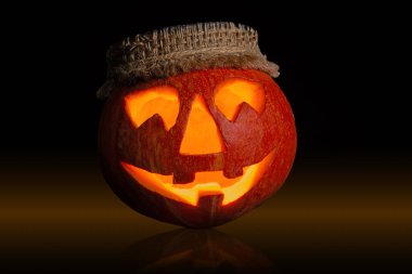 The carved pumpkin displays a mischievous grin with menacing eyes, illuminated from within, creating a spooky ambiance perfect for Halloween celebrations. clipart