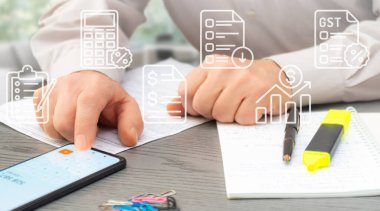 Bir kişi akıllı telefondaki kripto para birimi verilerini gözden geçirir ve çağdaş ofis ortamındaki pazar eğilimlerini analiz ederken notlar alır.
