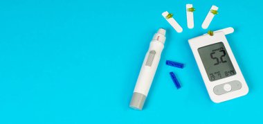 Kan şekeri ölçer ve insülin kalemini test şeritleri ve mızraklarıyla mavi bir arka plana yerleştirip diyabet yönetimi için yanlarına yerleştirmişler..
