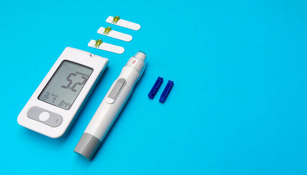 Глюкоза в крови и инсулиновая ручка помещены на синем фоне с тестовыми полосками и ланцетами, организованными рядом с ними для лечения диабета.