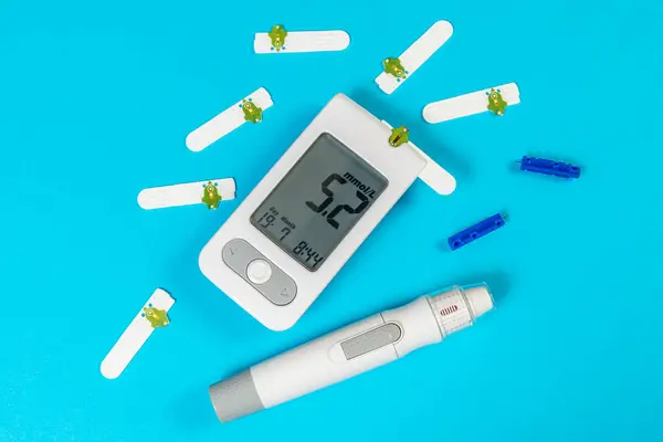 Kan şekeri ölçer ve insülin kalemini test şeritleri ve mızraklarıyla mavi bir arka plana yerleştirip diyabet yönetimi için yanlarına yerleştirmişler..