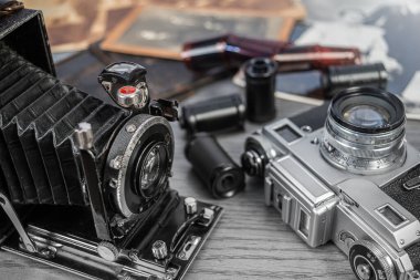 İki antika kamera, eski fotoğrafların olduğu bir koleksiyonun yanında oturup tuhaf bir çalışma ortamında nostalji hissi uyandırıyor..