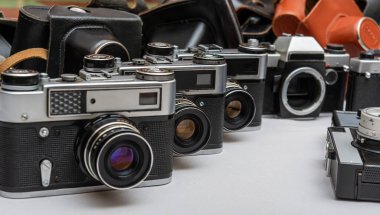 Bir yüzeye yerleştirilmiş eski kameralar, çeşitli stil ve materyalleri vurguluyor, fotoğrafçılık tarihine nostaljik bir bakış..