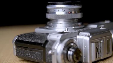 Retro-stil analog kamera, film kartuşları ve ahşap bir yüzeye karşı estetik olarak sergilenen sarılmış negatifler nostaljik anları anımsatıyor ve klasik fotoğrafçılığın özünü yakalıyor..