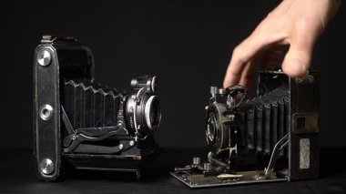 Klasik fotoğraf makinesi, klasik fotoğraf ekipmanlarını sergileyen bir adamın elinden kalkıyor.