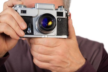 Bir adam elinde eski bir kamera tutuyor, anı yakalamaya hazır, fotoğrafçılığa ve klasik ekipmanlara olan aşkını somutlaştırıyor..