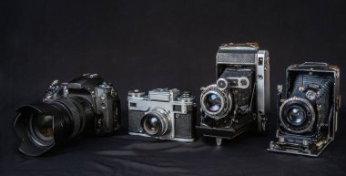Vintage 'dan modern' e farklı kamera stilleri karanlık bir yüzeyde yan yana oturarak zaman içinde fotoğraf teknolojisindeki gelişmeleri vurguluyor..