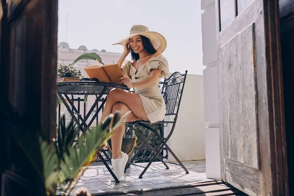Красива Молода Жінка Елегантному Капелюсі Читає Книгу Посміхається Відпочиваючи Балконі — стокове фото
