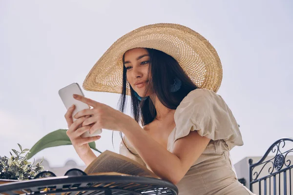 Hermosa Mujer Joven Sombrero Elegante Usando Teléfono Inteligente Mientras Relaja — Foto de Stock