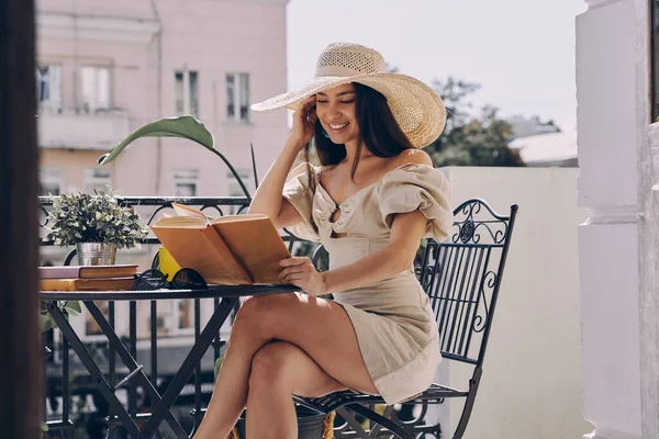 Приваблива Молода Жінка Елегантному Капелюсі Читає Книгу Посміхається Відпочиваючи Балконі — стокове фото