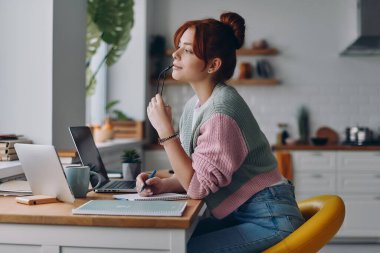 Evdeki mutfakta çalışırken düşünceli görünen güzel bir kadın.