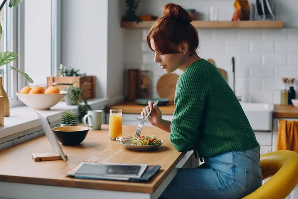 Красивая Молодая Женщина Обедает Смотрит Цифровой Планшет Сидя Кухонным Столом — стоковое фото