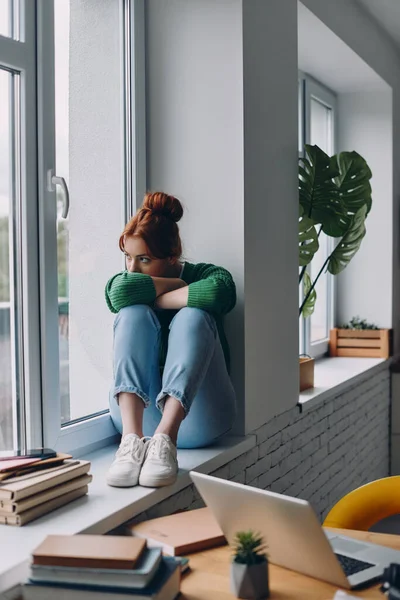 Ung Rödhårig Kvinna Som Ser Deprimerad När Hon Sitter Fönsterbrädan — Stockfoto