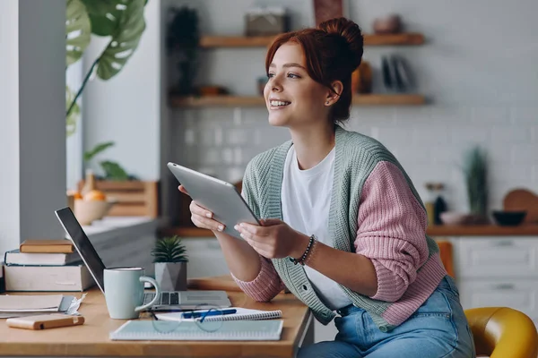 Mulher Bonita Usando Tablet Digital Sorrindo Enquanto Sentada Balcão Cozinha — Fotografia de Stock