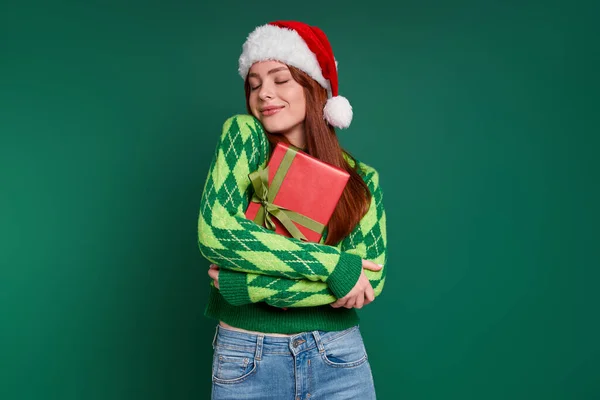Привлекательная Молодая Женщина Рождественской Шляпе Подарочной Коробкой Улыбкой Зеленом Фоне — стоковое фото