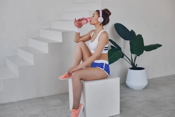 Mooie Jonge Vrouw Sport Kleding Drinkwater Terwijl Ontspannen Training Binnen — Stockfoto