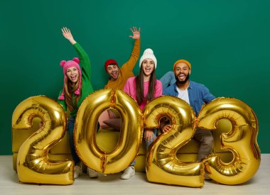 Birlikte kanepede otururken altın renkli numaralar taşıyan neşeli insanların stüdyo fotoğrafları.