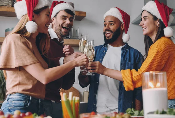 快乐的人们一边在家里享用圣诞大餐一边用香槟祝酒 — 图库照片