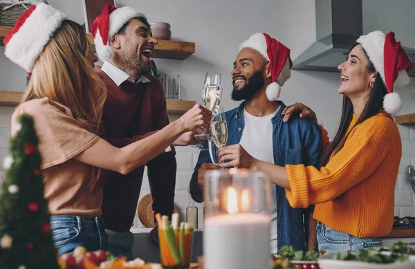 自宅でクリスマスディナーを楽しみながら シャンパンで乾杯する陽気な若者たち — ストック写真